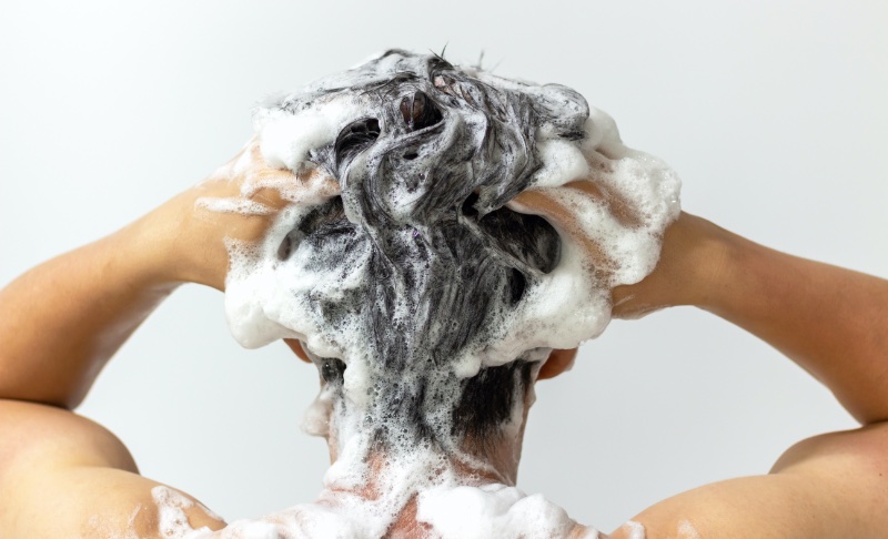 man shampooing curly hair