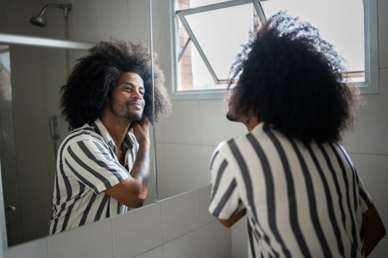 man styling curly hair mirror