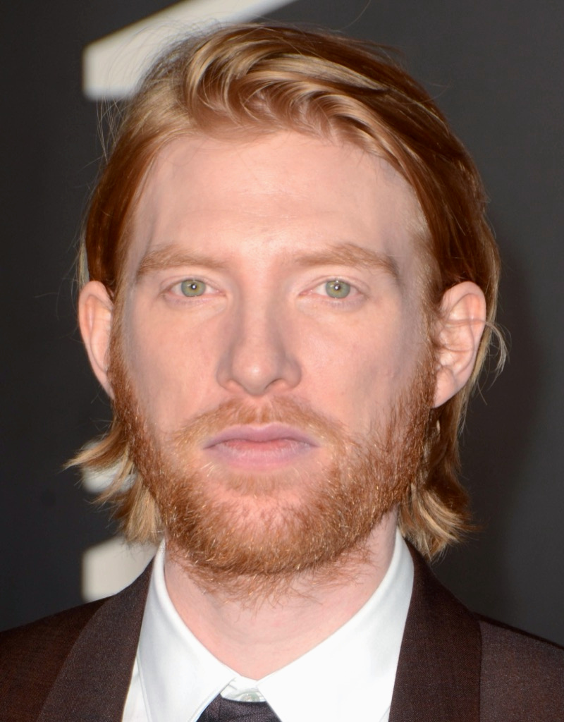 Domhnall Gleeson with long red hair swept back from his face
